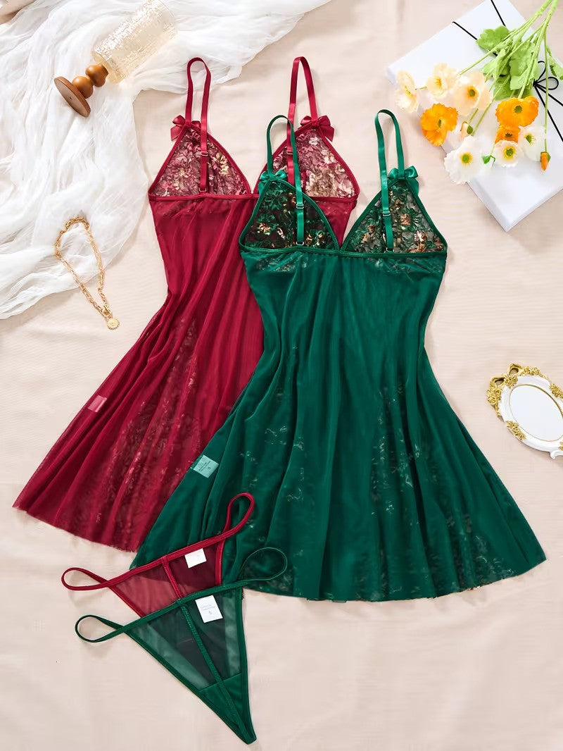 Two green and red lace nightgowns on a beige surface with flowers and jewelry.