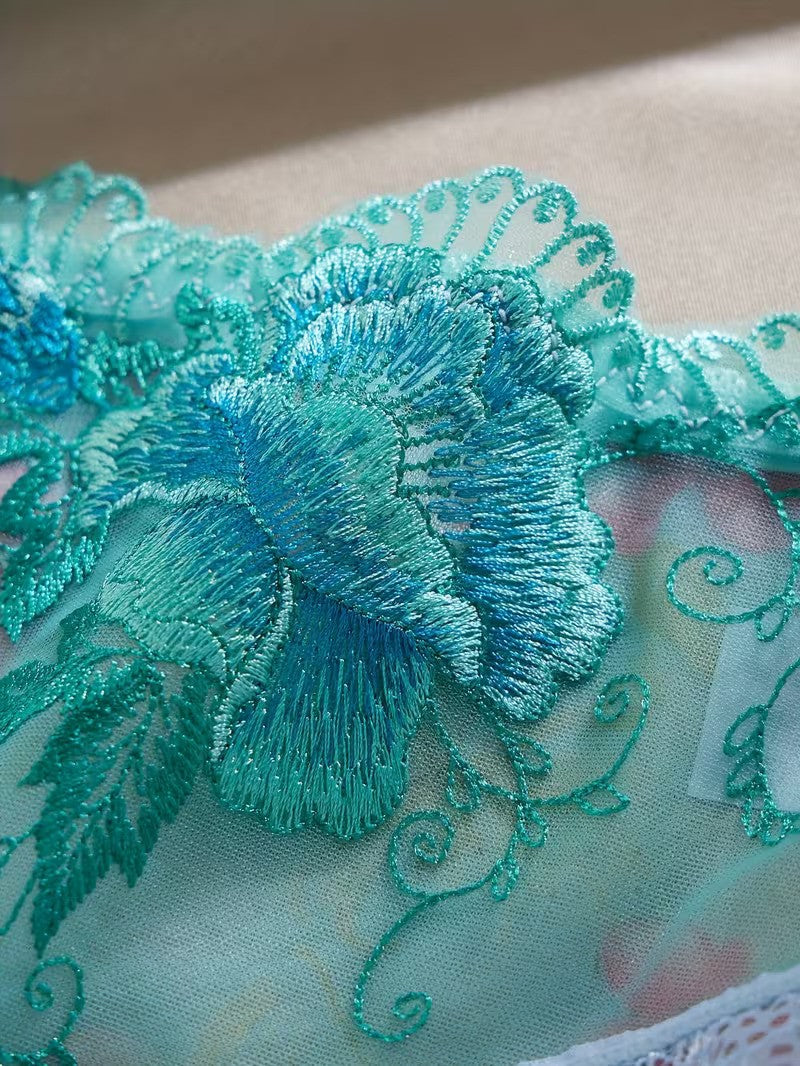 Close-up of teal embroidered fabric with floral design