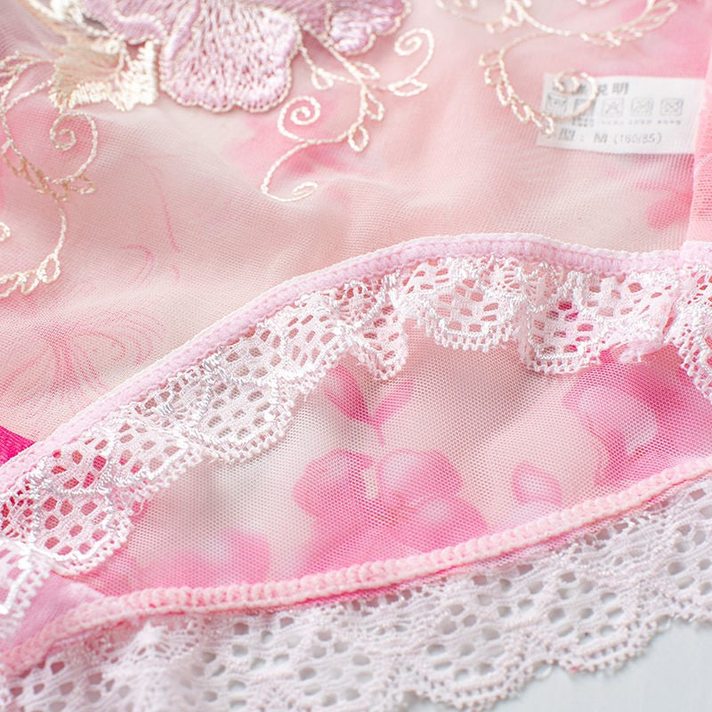 Close-up of pink fabric with lace trim and floral embroidery