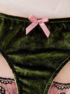 Green velvet thong underwear with a pink satin bow at the center front and a thin pink lace trim, shown against a pale pink background.